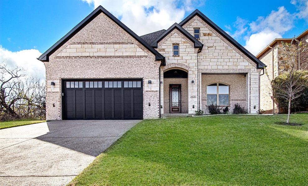 French provincial home featuring a garage and a front yard