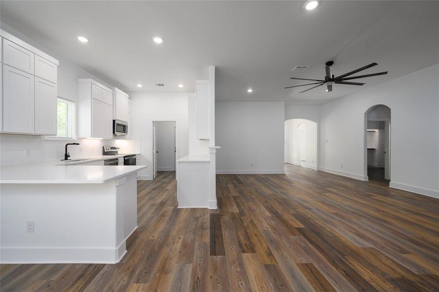 Kitchen with white cabinetry, appliances with stainless steel finishes, sink, dark wood-type flooring, and kitchen peninsula