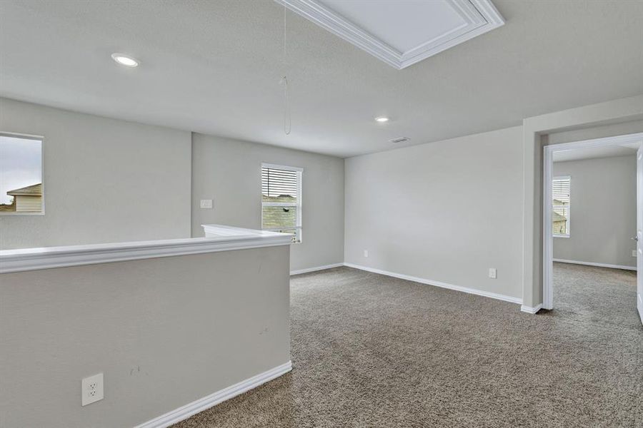 Spacious room featuring neutral carpeting, recessed lighting, and a white ceiling hatch