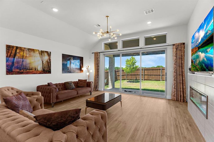 Living room with a chandelier, wood finished floors, lofted ceiling, a fireplace, and recessed lighting Living room with a chandelier, wood finished floors, lofted ceiling, a fireplace, and recessed lighting