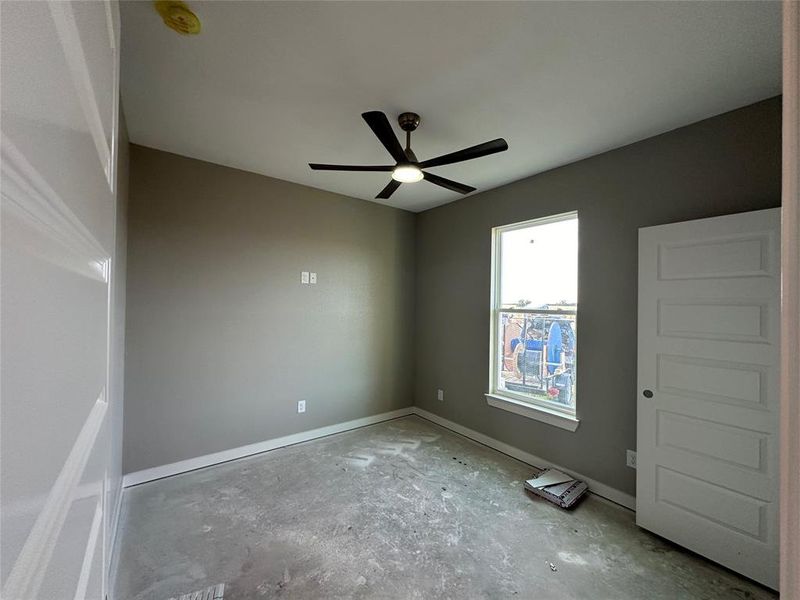 Unfurnished room with concrete flooring and ceiling fan