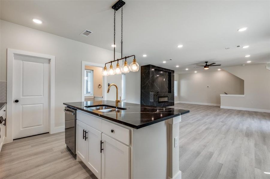 Kitchen with pendant lighting, white cabinetry, a center island with sink, a ceiling fan, and open floor plan