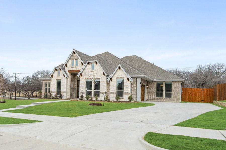 Single-story home with stone and brick exterior, curved driveway, and manicured front lawn Single-story home with stone and brick exterior, curved driveway, and manicured front lawn
