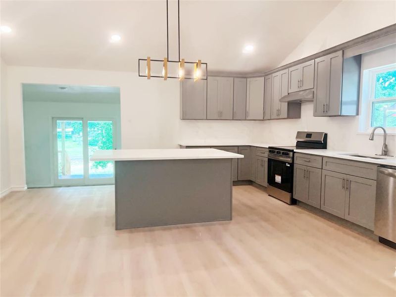Modern kitchen featuring light gray cabinetry, a central island with white countertop, and stainless steel appliances