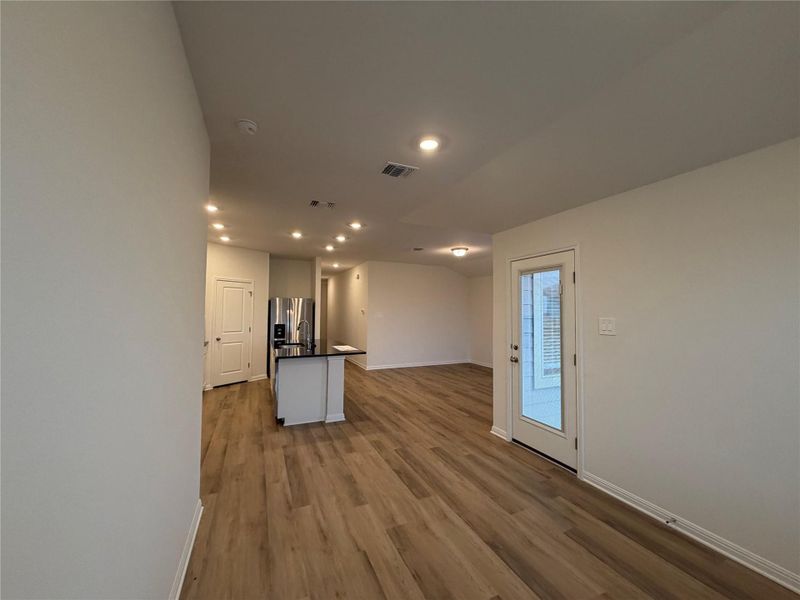 Kitchen with dark countertops, open floor plan, recessed lighting, a center island with sink, and dark wood-style floors Kitchen with dark countertops, open floor plan, recessed lighting, a center island with sink, and dark wood-style floors