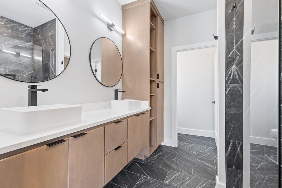 Full bathroom featuring dark marble finish flooring, double vanity, and a marble finish shower