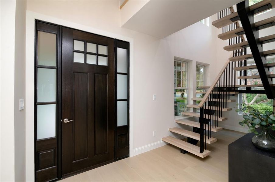 Entrance foyer with light wood-type flooring and a towering ceiling