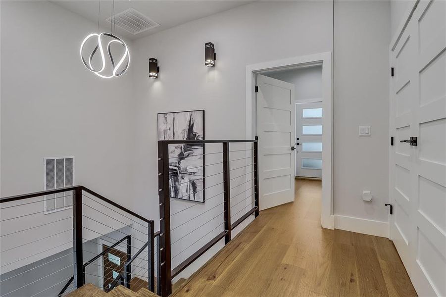 Clean lines and warm wood floors define this inviting entryway with modern lighting.
