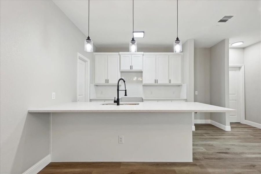 Kitchen with sink, wood-type flooring, and white cabinets