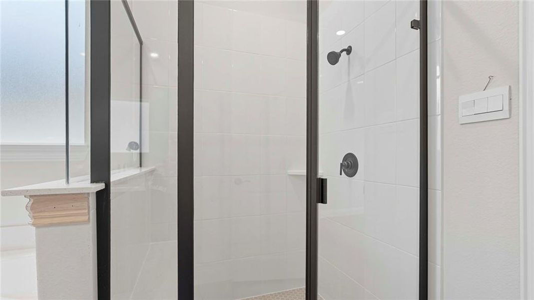 Enclosed shower featuring a clear glass and matte black frame, white tiled walls, a built-in shelf, and dark-finish fixtures