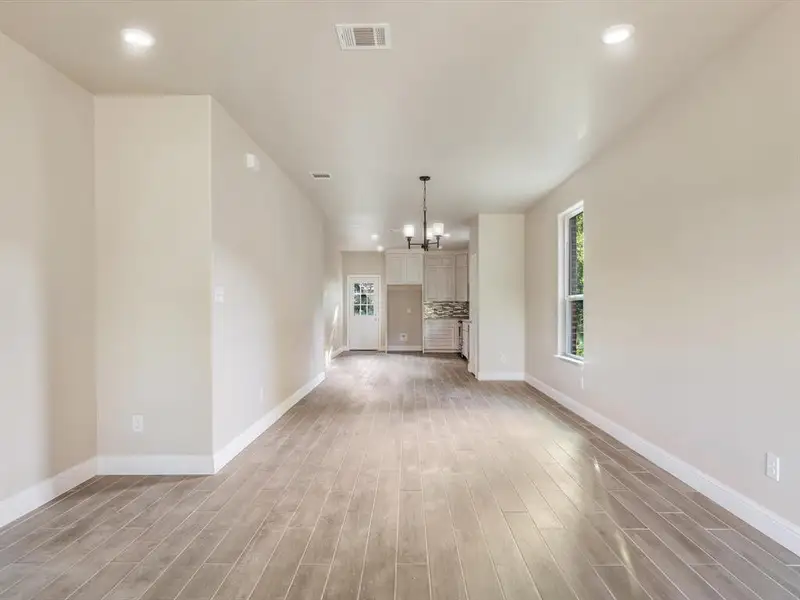 Unfurnished living room featuring healthy amount of natural light, light wood-style floors, a chandelier, and recessed lighting Unfurnished living room featuring healthy amount of natural light, light wood-style floors, a chandelier, and recessed lighting