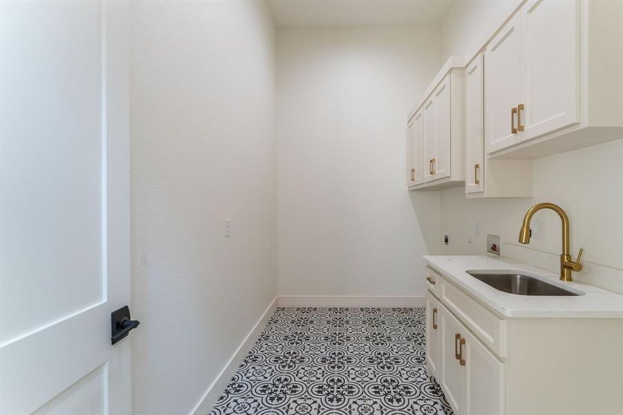 Washroom with hookup for a washing machine, cabinet space, hookup for an electric dryer, and light tile patterned floors