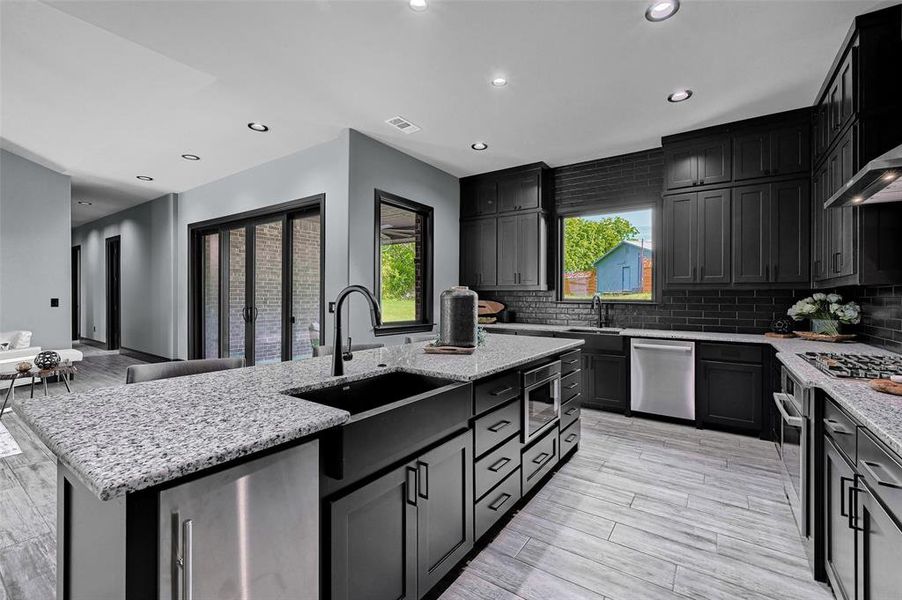 Kitchen featuring stainless steel appliances, a sink, light stone countertops, tasteful backsplash, and recessed lighting Kitchen featuring stainless steel appliances, a sink, light stone countertops, tasteful backsplash, and recessed lighting