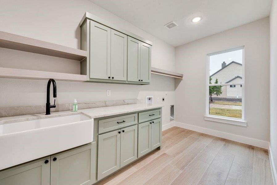 Laundry area with cabinets, sink, hookup for an electric dryer, light hardwood / wood-style flooring, and hookup for a washing machine