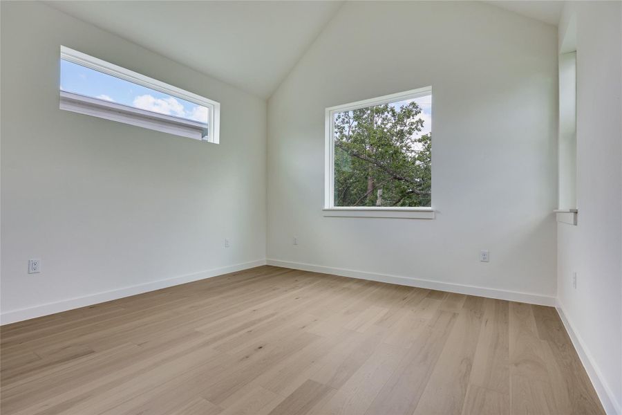 Vaulted ceilings complement light wood flooring in this serene, sun-drenched room.