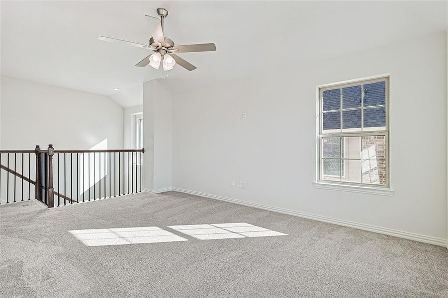 Empty room featuring light colored carpet, ceiling fan, and lofted ceiling