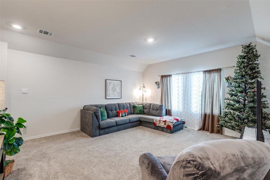 Living room with lofted ceiling, carpet floors, and recessed lighting Living room with lofted ceiling, carpet floors, and recessed lighting