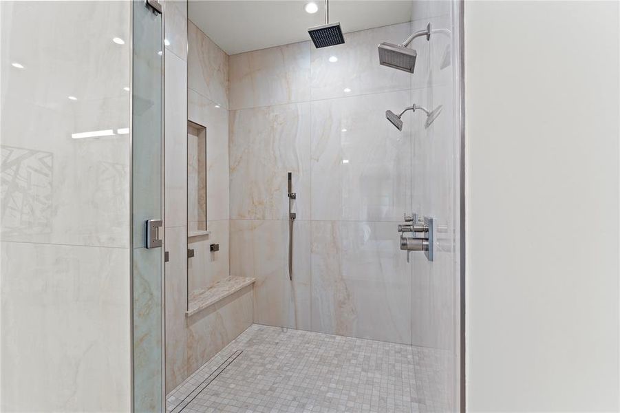 Huge shower has two main shower heads, a rain head, a hand held, and multiple body sprays.