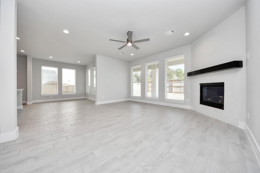 Welcome family and guests to your charming living room! With its high ceilings, recessed lighting, ceiling fan, custom paint, beautiful flooring, and large windows that let in abundant natural light, this room is perfect for gatherings.