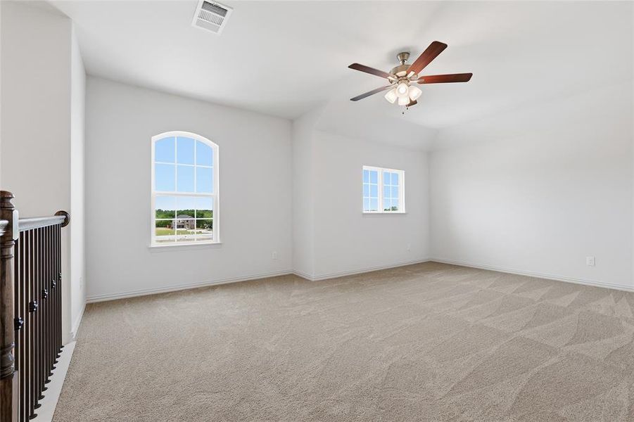 Spacious carpeted room featuring a vaulted ceiling and an arched window