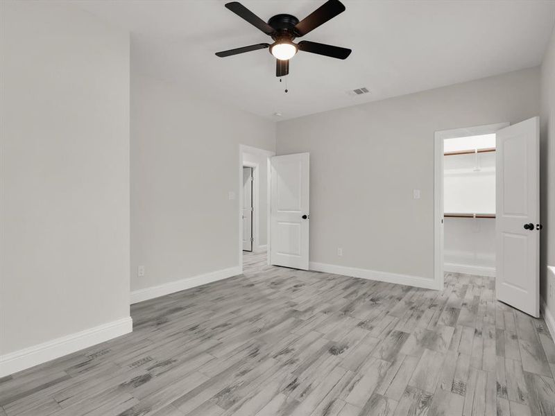 Unfurnished bedroom with ceiling fan, light hardwood / wood-style floors, a spacious closet, and a closet