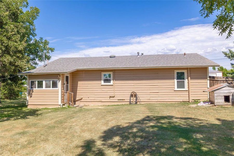 Back of property with a shingled roof and a yard Back of property with a shingled roof and a yard