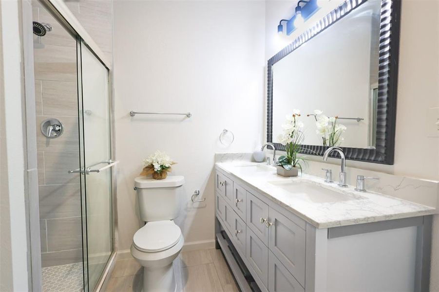 Bathroom featuring double vanity and tiled shower
