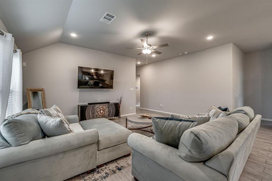 Living room with light hardwood / wood-style floors, ceiling fan, and vaulted ceiling