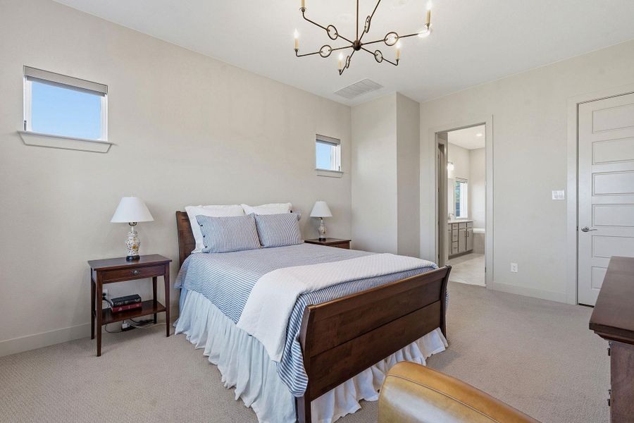 Bedroom featuring light carpet, a chandelier, and ensuite bath Bedroom featuring light carpet, a chandelier, and ensuite bath