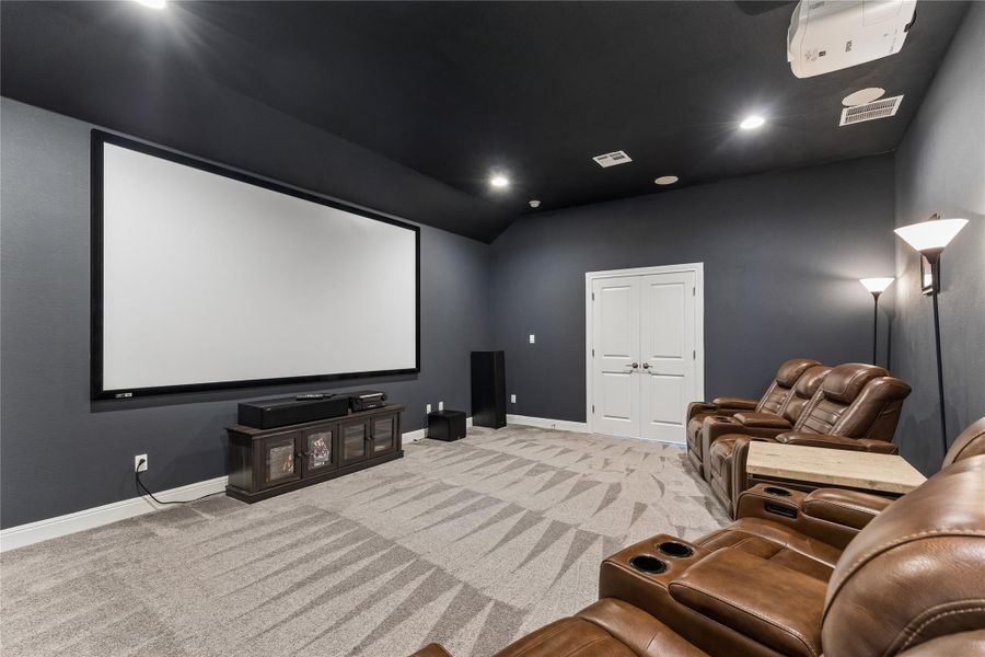 Experience cinematic bliss in this home theater featuring a large projection screen and plush seating.