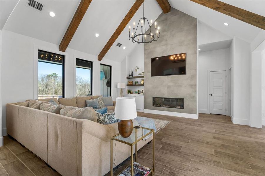 Living area with high vaulted ceiling, an inviting chandelier, beamed ceiling, visible vents, and recessed lighting Living area with high vaulted ceiling, an inviting chandelier, beamed ceiling, visible vents, and recessed lighting