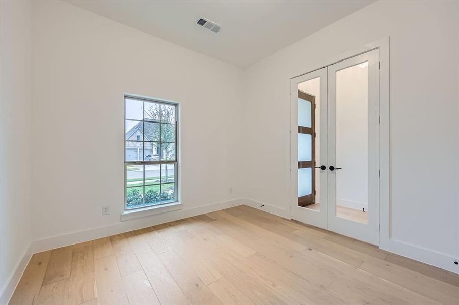 Empty room with french doors and light hardwood / wood-style flooring