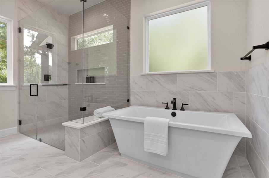 This bathroom showcases elegant tilework including marble-look tile surrounding the freestanding tub and sleek subway tile that extends to the ceiling in the walk-in shower accented by built-in shelving and matte black fixtures.