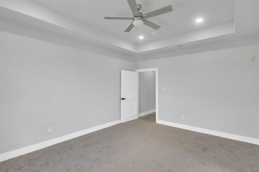 Empty room featuring a tray ceiling, carpet floors, recessed lighting, and ceiling fan