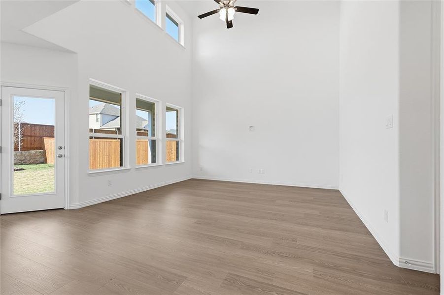 Unfurnished room featuring wood finished floors, a high ceiling, and ceiling fan
