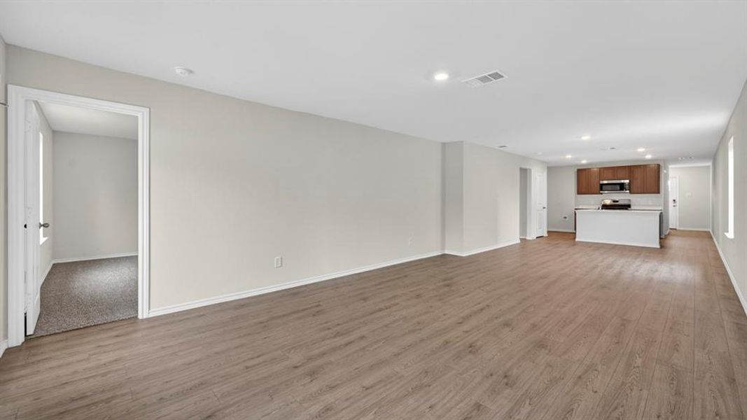 Spacious open-concept living area featuring wood-finish flooring, recessed lighting, and light-toned wall paint Spacious open-concept living area featuring wood-finish flooring, recessed lighting, and light-toned wall paint