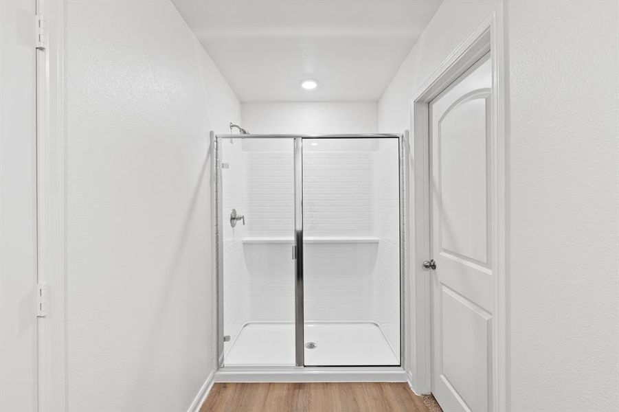 Bathroom with wood-type flooring and a shower with door