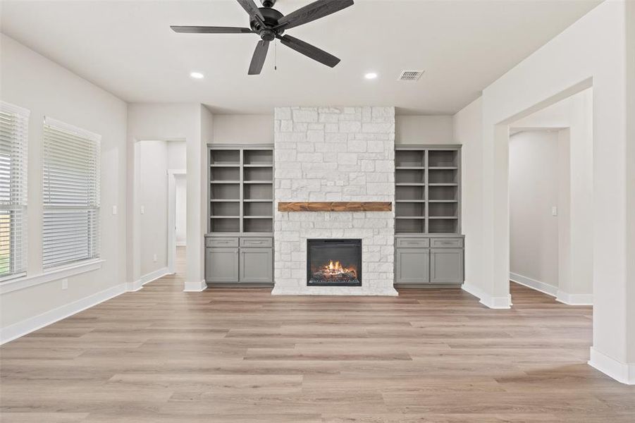 Unfurnished living room featuring a ceiling fan, a stone fireplace, light wood-style flooring, and recessed lighting