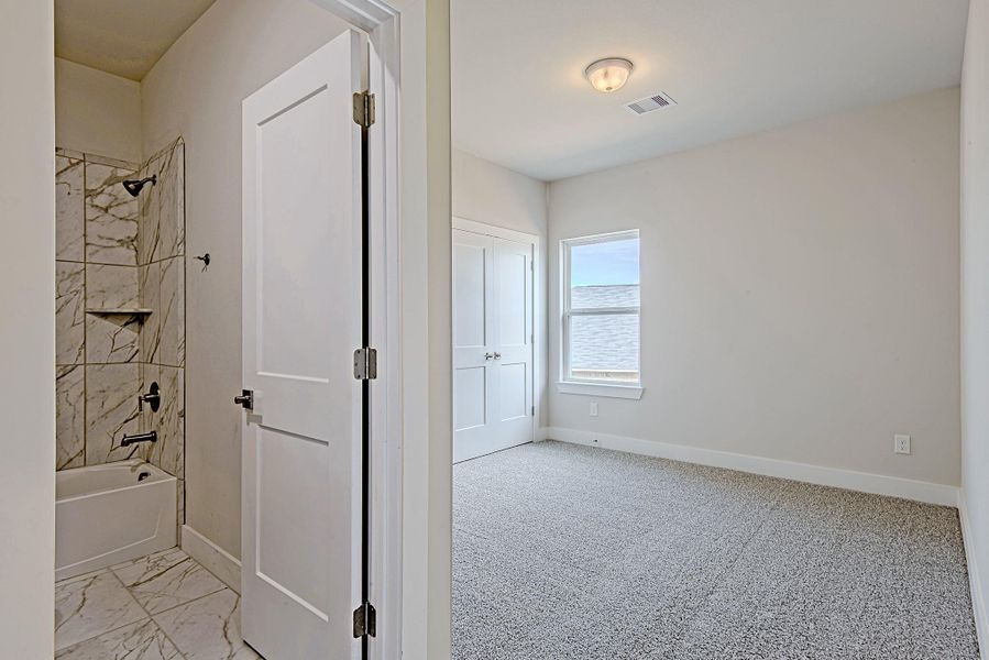 A peek into another secondary bedroom with a full ensuite bathroom nearby, ideal for guests, teens, or offering guests a bit more privacy. A peek into another secondary bedroom with a full ensuite bathroom nearby, ideal for guests, teens, or offering guests a bit more privacy.