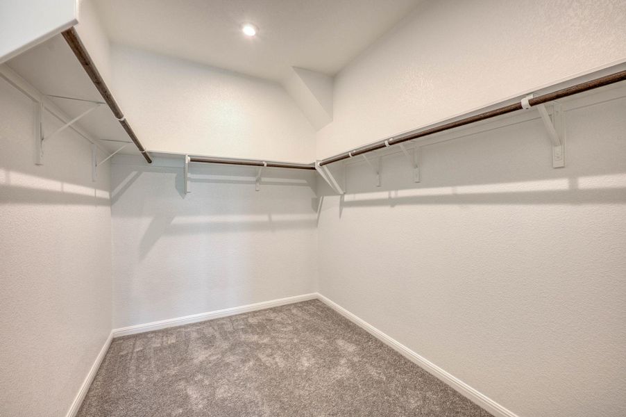 Ample hanging rods and shelving wrap around this carpeted walk-in closet.