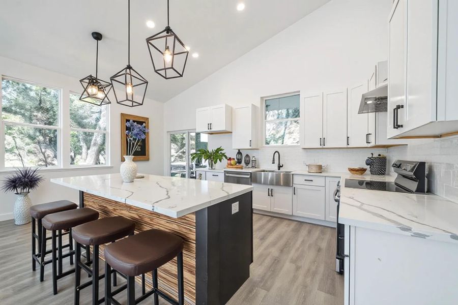 Soaring ceilings and a generous island anchor this modern culinary workspace with wood-look flooring. Soaring ceilings and a generous island anchor this modern culinary workspace with wood-look flooring.