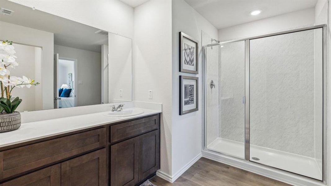 Full bath with a stall shower, vanity, and light wood-style floors