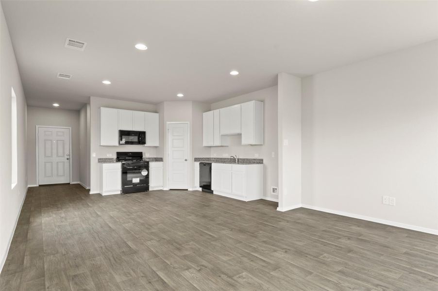 Kitchen featuring white cabinets, recessed lighting, black appliances, dark wood-style flooring, and open floor plan