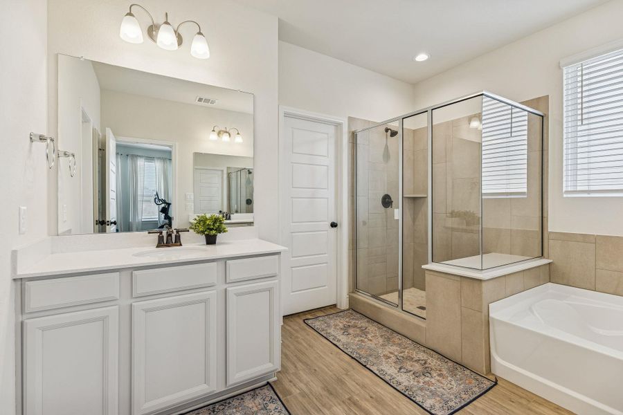 Spacious walk-in shower in primary bathroom and dual vanities