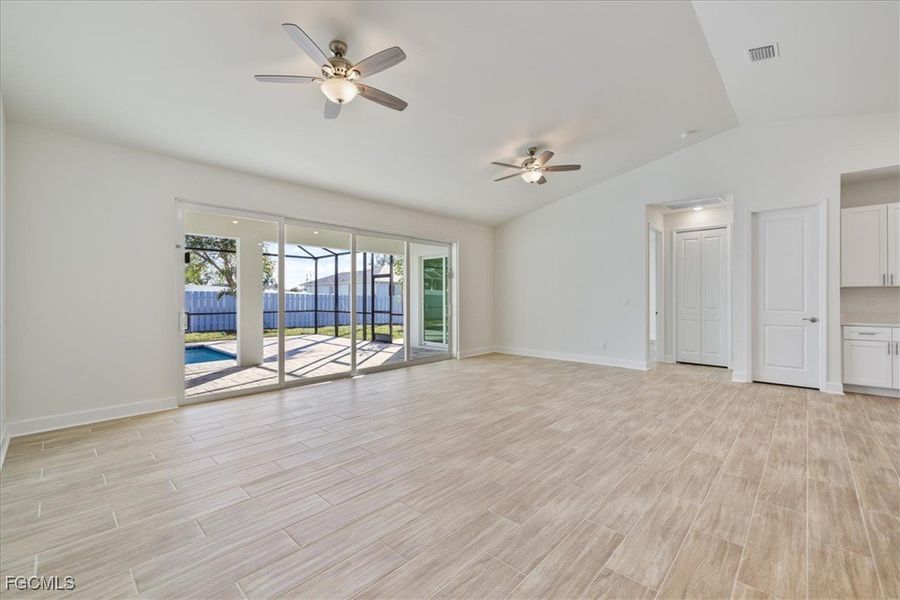 Unfurnished living room featuring vaulted ceiling, wood tiled floors, and a ceiling fan