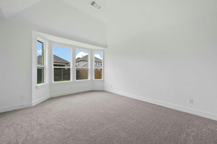 Carpeted empty room featuring baseboards, lofted ceiling, and visible vents