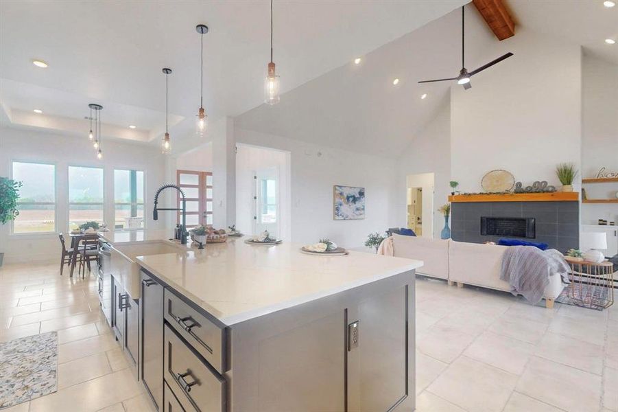 Kitchen with decorative light fixtures, recessed lighting, open floor plan, an island with sink, and light stone countertops Kitchen with decorative light fixtures, recessed lighting, open floor plan, an island with sink, and light stone countertops