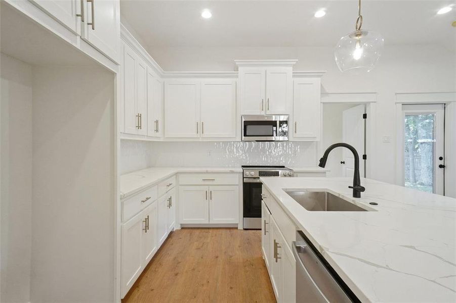 Kitchen with appliances with stainless steel finishes, light wood-style floors, white cabinets, decorative backsplash, and recessed lighting