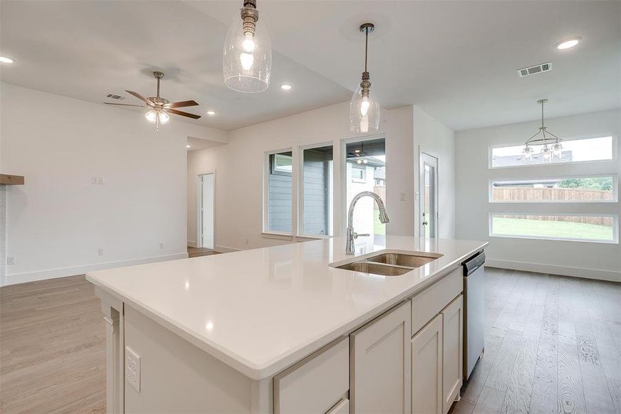 Kitchen featuring a center island with sink, sink, ceiling fan, and light hardwood / wood-style flooring