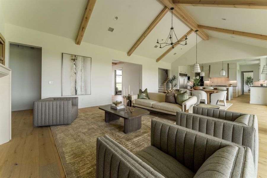 Living room featuring light wood-style flooring, high vaulted ceiling, beam ceiling, and a chandelier Living room featuring light wood-style flooring, high vaulted ceiling, beam ceiling, and a chandelier
